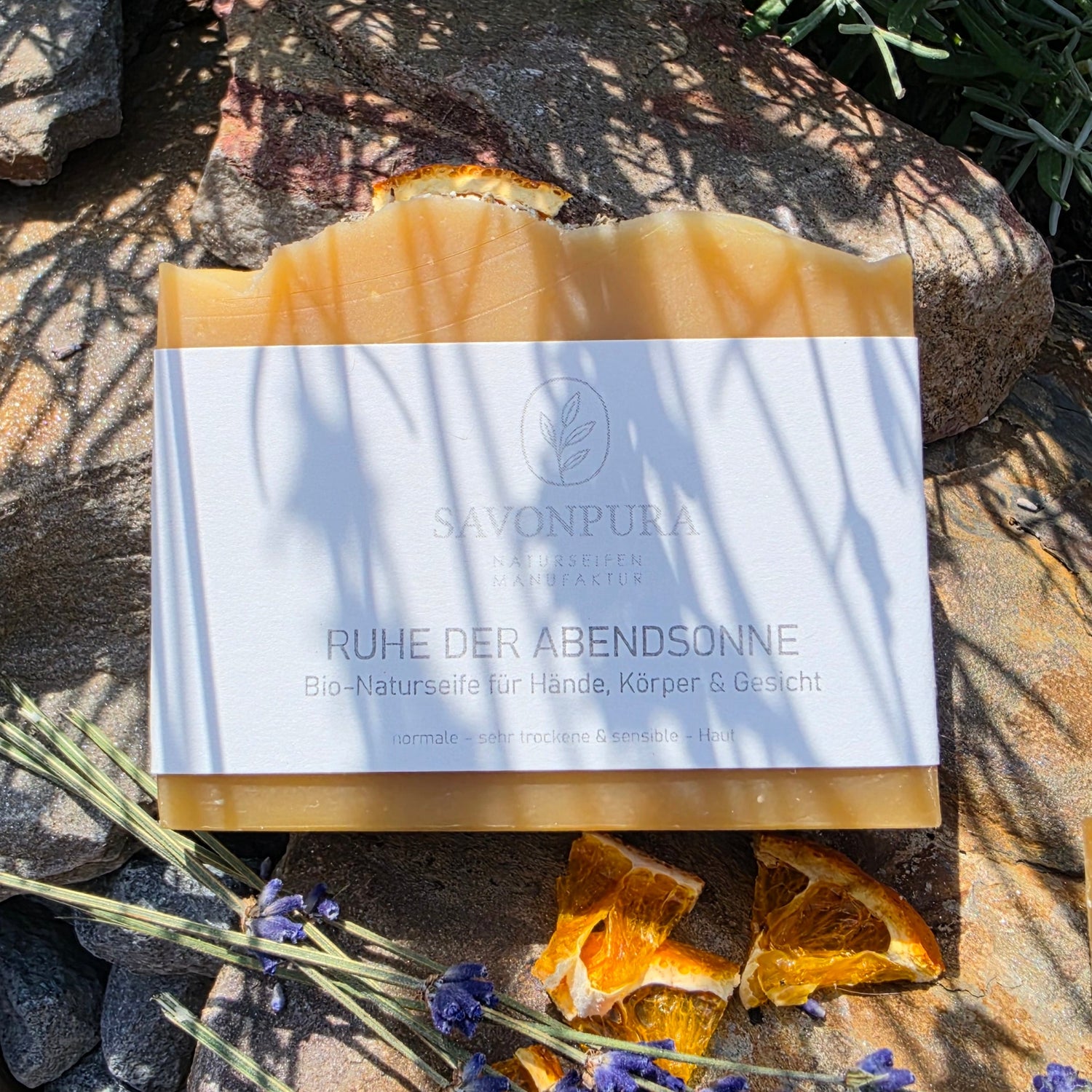 Bio-Naturseife liegend auf Naturstein mit Orangenstücken und Lavendel