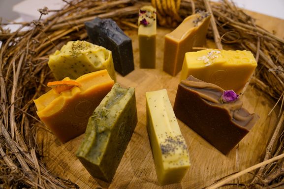 Bunte handgemachte Seifenstücke angeordnet in einem kreisförmigen Muster auf Holz.