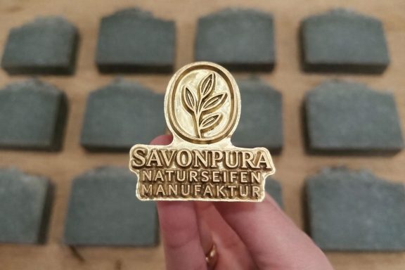 Handgefertigter Messing-Seifenstempel mit dem Logo SAVONPURA Naturseifen Manufaktur. Jedes Seifenstück wird einzeln von Hand geprägt.