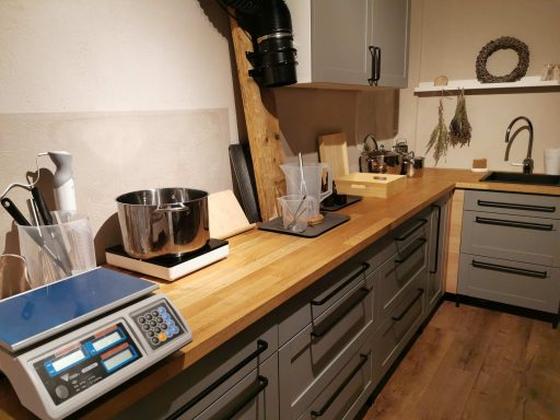 Landhausküche mit Holzarbeitsplatte, Waage, Mixgerät und verschiedenen Küchenutensilien.