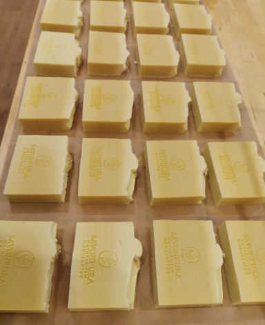 Goldfarbene Seifenstücke auf einem Holzbrett, ordentlich angeordnet.